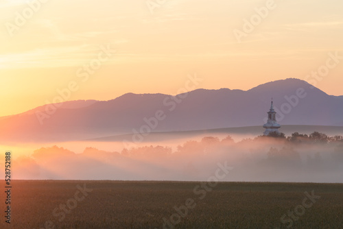 Church of Pribovce village shrouded in morning fog, Slovakia.