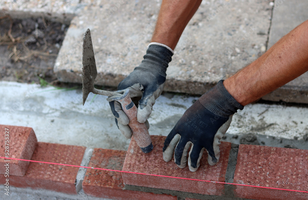 Construction work in progress. Male builder working with red bricks. Masonry wall close up photo. Construction work in progress. Male builder working with red bricks. Masonry wall close up photo.