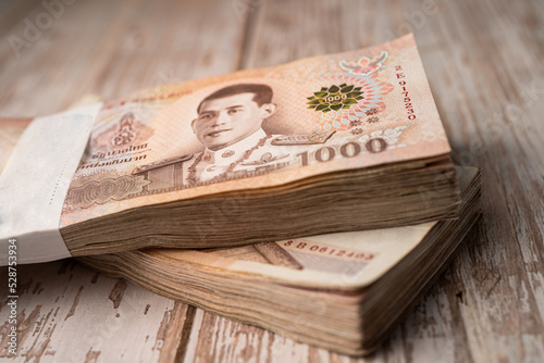 Fotografie Stack of Thai baht banknotes on wooden background, business saving finance investment concept