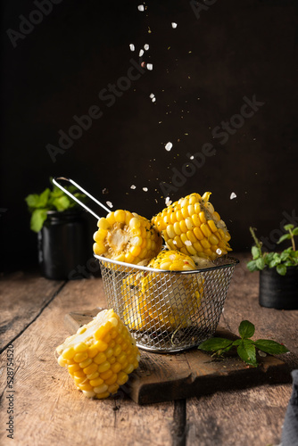 boiled corn cob. with salt and spices. vertical image. for advertising and menus. on a dark background