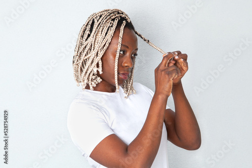 Mujer negra haciéndose las trenzas en su casa. Lifestyle