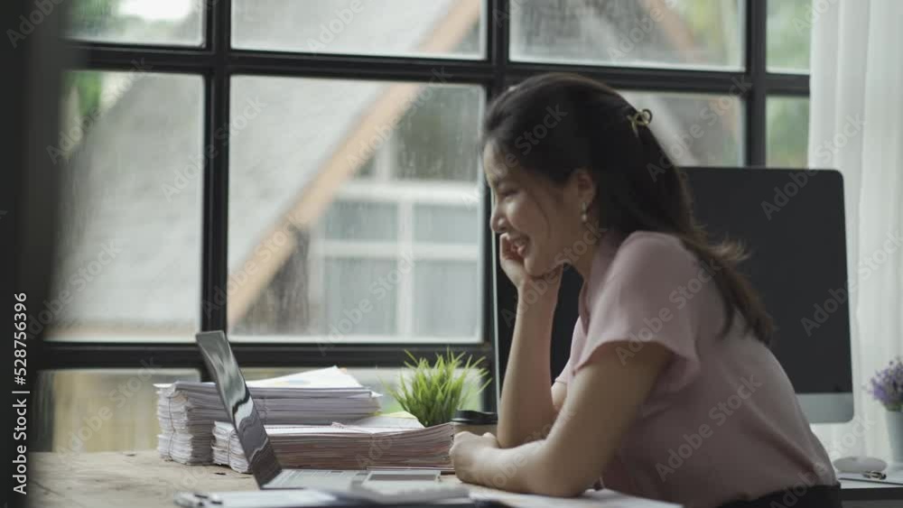 online business Asian female accountant working from home using laptop in meeting with smartphone, financial graphing calculator. online business Asian female accountant working from home using laptop in meeting with smartphone, financial graphing calculator.