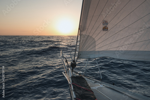 Sailing into the sunset on a yacht traveling through the atlantic ocean 
