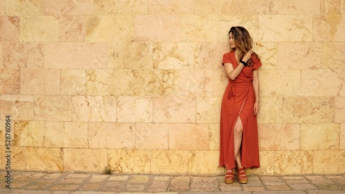 woman standing in red dress on the sidewalk © Esteve