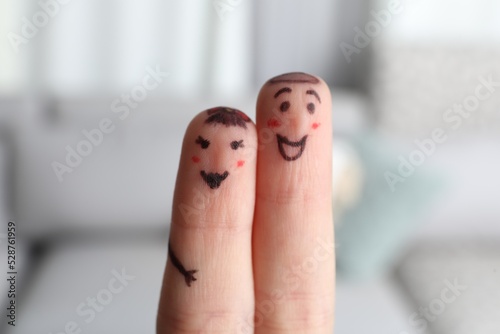 Two fingers with drawings of happy faces on blurred background. Spending time together