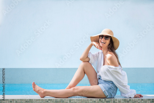 Happy woman sitting by a swimming pool