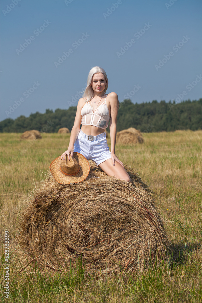 Young beautiful blonde girl in a straw hat posing in the hayloft Young beautiful blonde girl in a straw hat posing in the hayloft