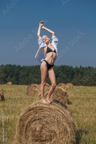 Sexy young woman in a straw hat lies on a haystack