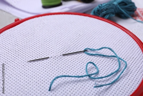 Embroidery hoop with fabric and needle, closeup photo