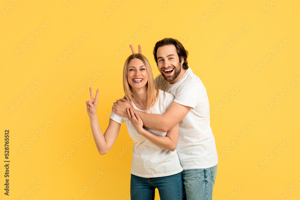 Cheerful funny millennial caucasian woman and man in white t-shirts have fun, show peace sign with hands Cheerful funny millennial caucasian woman and man in white t-shirts have fun, show peace sign with hands