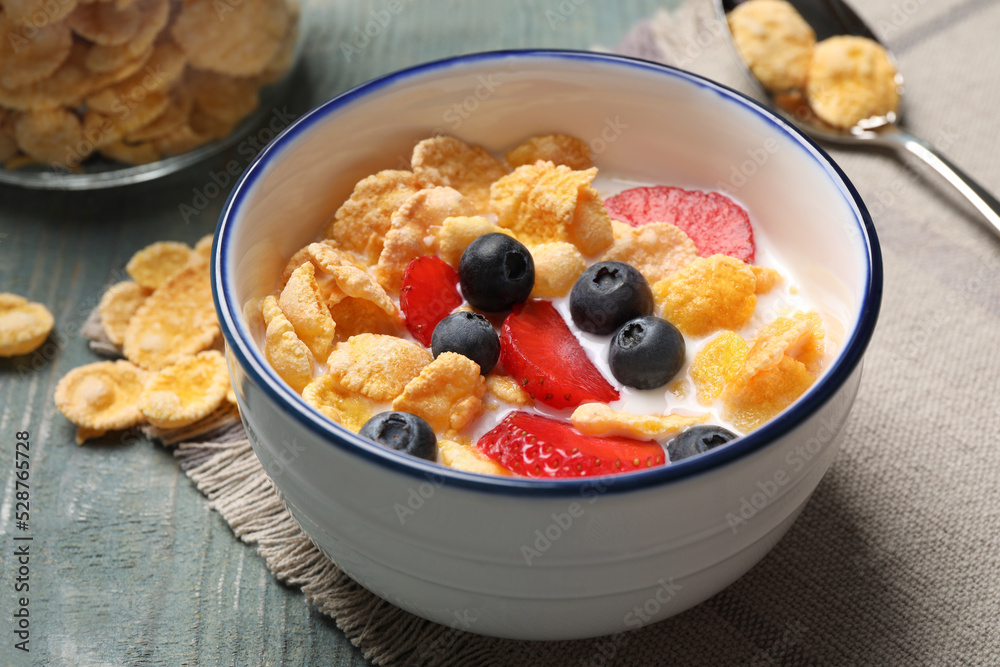 Delicious crispy cornflakes with milk and fresh berries on light blue wooden table, closeup Delicious crispy cornflakes with milk and fresh berries on light blue wooden table, closeup