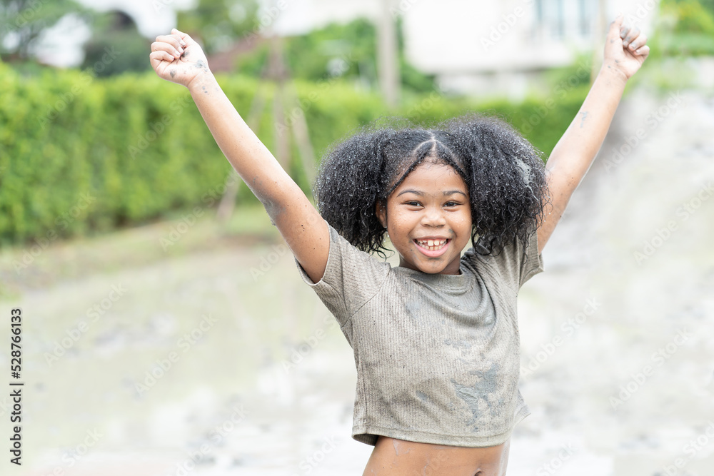 Happy African American child girl playing in large wet mud puddle and dirt on summer day Happy African American child girl playing in large wet mud puddle and dirt on summer day