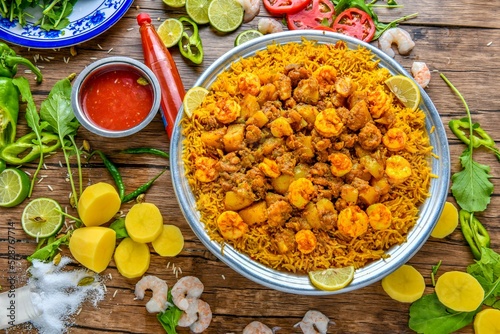 Kabsa Shrimp garnished with potatoes, lime slice, and ketchup top view on wooden table middle east food