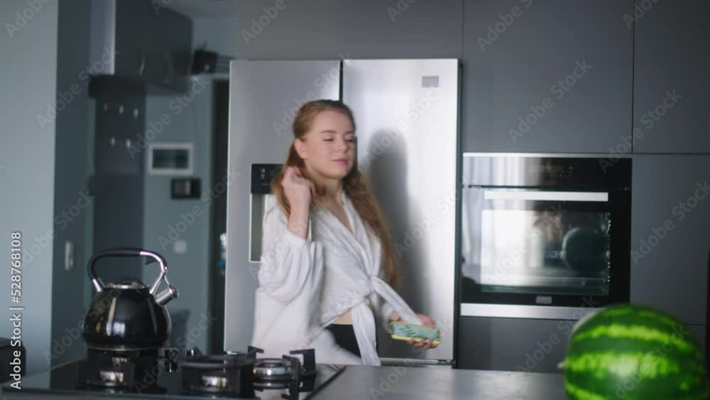 Economical inflation. Woman in the kitchen looking at cash receipt and counting after shopping. Girl checks bill and calculates expenses at home after buying groceries. Female looking at phone. Economical inflation. Woman in the kitchen looking at cash receipt and counting after shopping. Girl checks bill and calculates expenses at home after buying groceries. Female looking at phone.