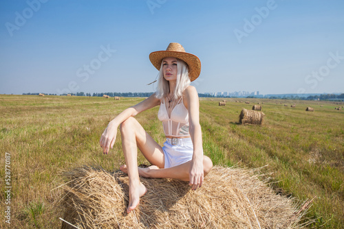 Obraz na płótnie Young beautiful blonde girl in a straw hat posing in the hayloft