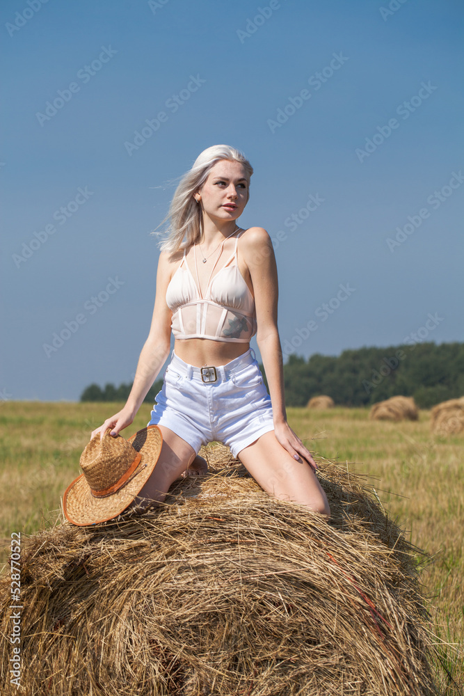 Young beautiful blonde girl in a straw hat posing in the hayloft Young beautiful blonde girl in a straw hat posing in the hayloft