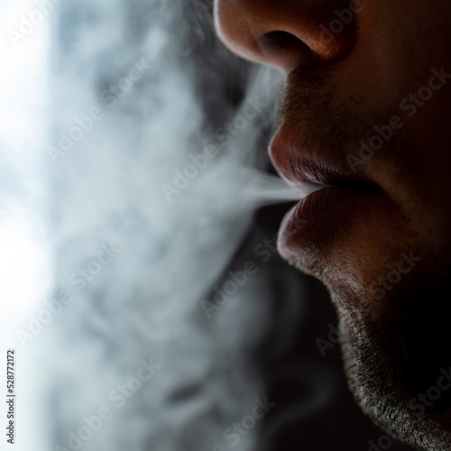 Seductive male lips blowing cigarette smoke.
