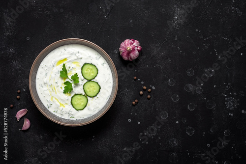 Greek tzatziki sauce on black stone background. View from above, flat lay