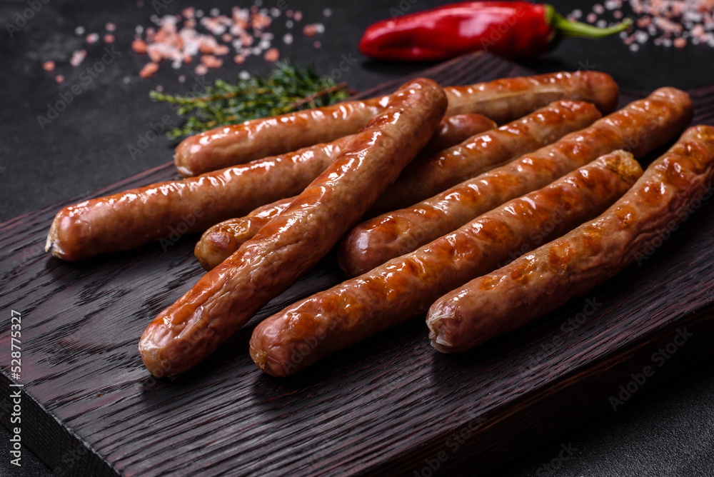 Grilled sausage with the addition of herbs and vegetables on the wooden cutting board Grilled sausage with the addition of herbs and vegetables on the wooden cutting board