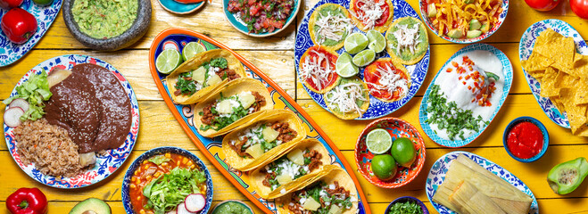 Mexican festive food for independence day independencia - chiles en nogada, tacos al pastor, chalupas pozole, tamales, chicken with mole poblano sauce. Yellow background.