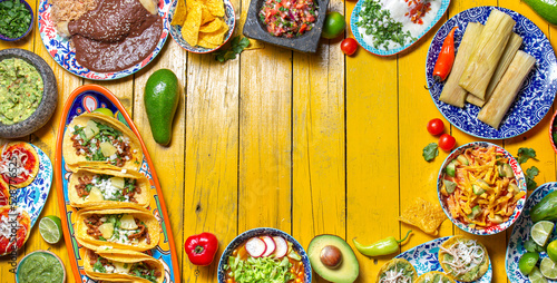 Mexican festive food for independence day independencia - chiles en nogada, tacos al pastor, chalupas pozole, tamales, chicken with mole poblano sauce. Yellow background.