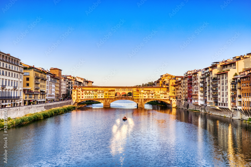 Golden Sunset over Ponte Vecchio Bridge with Traditional Boat on the Arno River