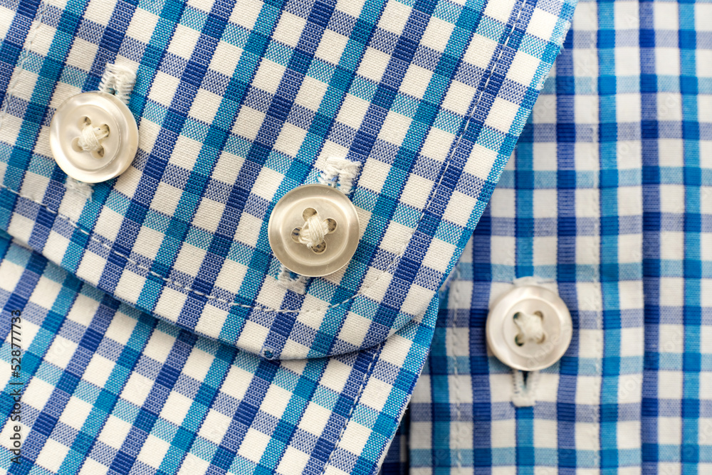 Buttons on the sleeve of the shirt in blue checkered material. Button Buttons on the sleeve of the shirt in blue checkered material. Button