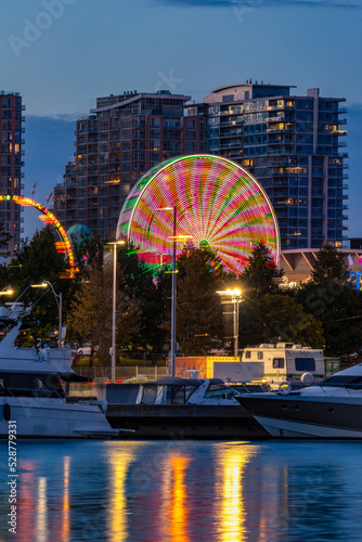 Photography Ferris wheel in motion at night, reflecting in water around boats