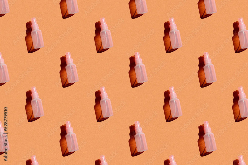 cosmetic spray bottle pink on orange background with hard light