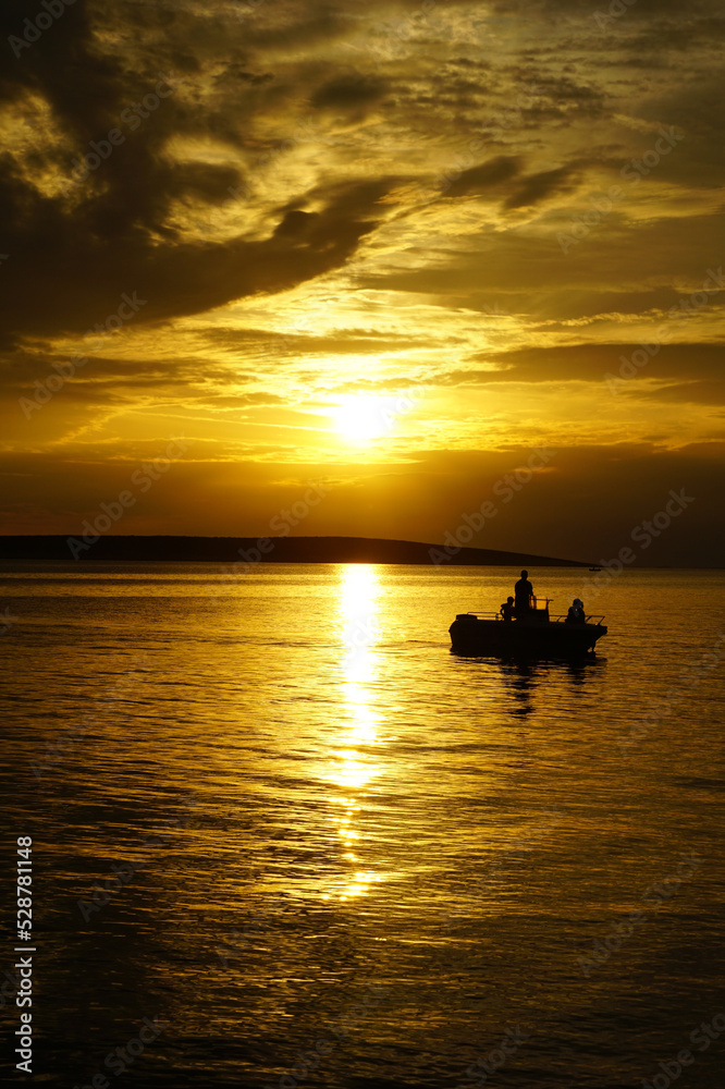 Family on a boat on a summer vacation in a beautiful sunset at sea