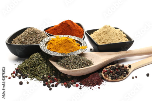 Turmeric powder, ginger ground, red paprika, anise seeds, colorful pepper, dry basil in wooden spoon, pile sumac and dry chopped parsley isolated on white