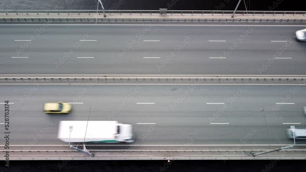 Flying over a modern highway bridge with heavy traffic across a wide river. Aerial view. Flying over a modern highway bridge with heavy traffic across a wide river. Aerial view.