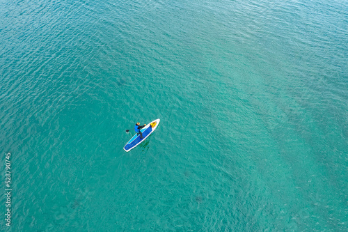 Man rowing oar on sup board blue sea water. Aerial top view paddleboard © Parilov