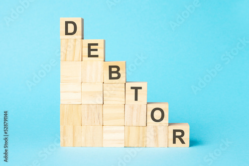 the word DEBTOR is written on a wooden cubes, concept Fototapet