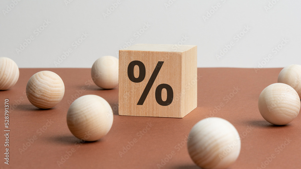 percent sign on wooden cubes against brown background with wooden balls. concept of sale and discount percent sign on wooden cubes against brown background with wooden balls. concept of sale and discount