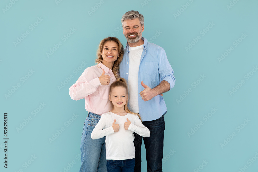 Happy Parents And Kid Daughter Gesturing Thumbs Up, Blue Background