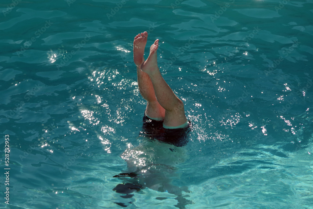 A man doing an underwater handstand in a swimming pool