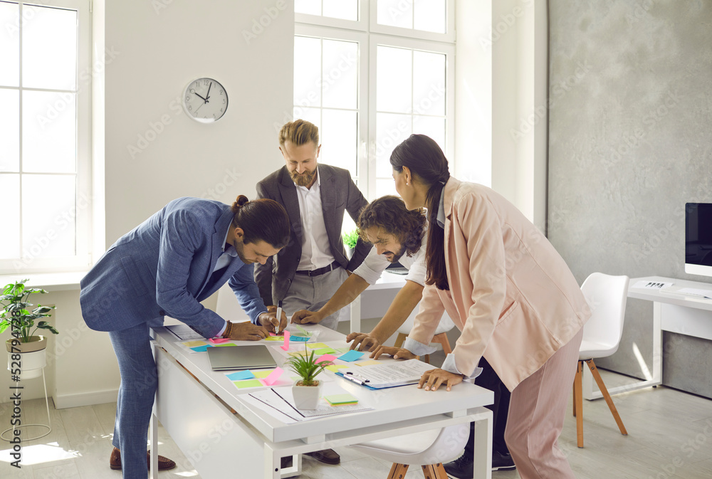 Obraz premium Diverse employees workers brainstorm involved in creative team thinking with paperwork in office. Multiracial businesspeople discuss business ideas work together on project. Teamwork concept.