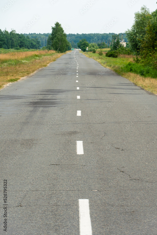 Empty asphalt road close-up against the background of the forest. Empty background, space for text. New asphalt concrete pavement in rural areas.