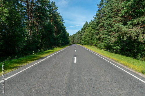 Empty asphalt road close-up against the background of the forest. Empty background, space for text. New asphalt concrete pavement in rural areas.