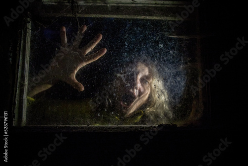 Fototapeta Naklejka Na Ścianę i Meble -  scary woman behind window  at night Halloween horror background