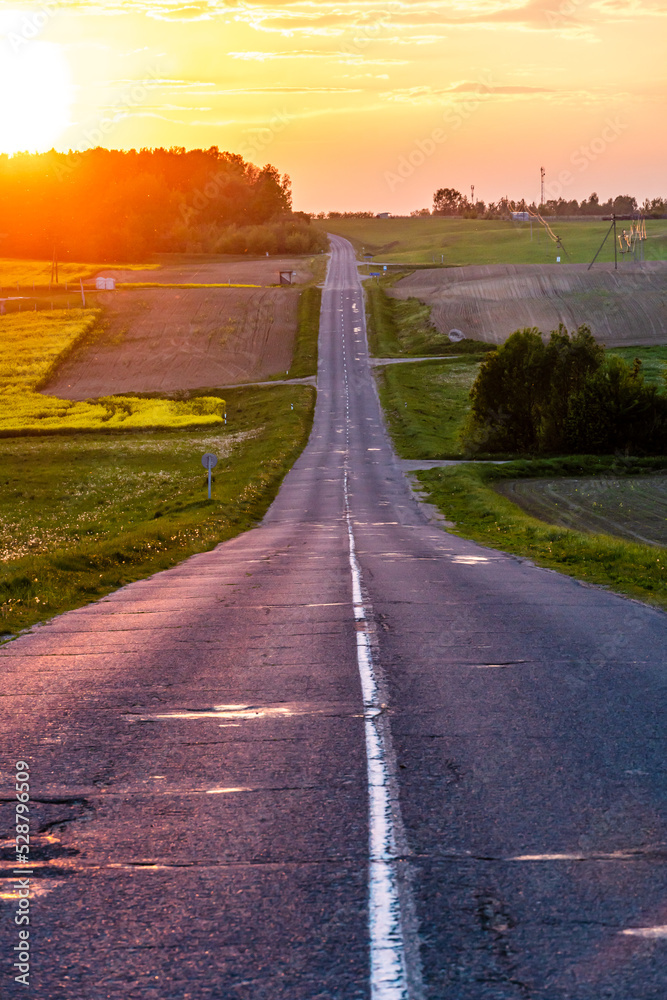 Panoramic view of a long empty asphalt road in a hilly area. The empty winding road goes far into the distance beyond the horizon.