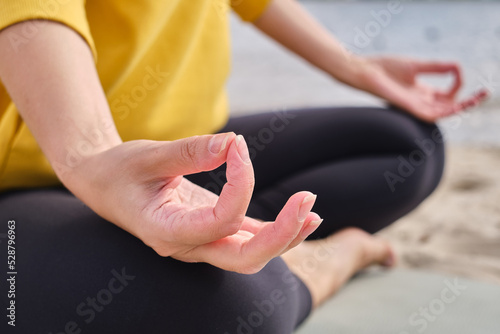 Women in sportswear sitting in lotus position and meditating during yoga class. Practicing yoga lesson, breathing, meditation, doing Ardha Padmasana exercises. Wellness concept