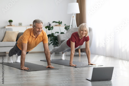Athletic senior spouses training at home  using notebook