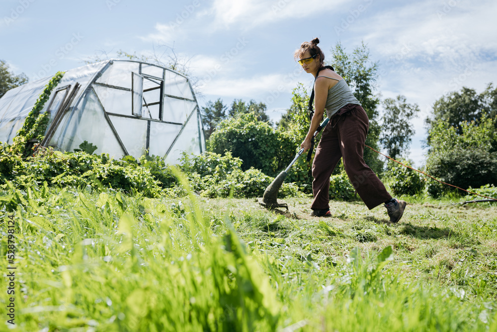 custom made wallpaper toronto digitalWoman cutting grass with a trimmer and a greenhouse in. the background