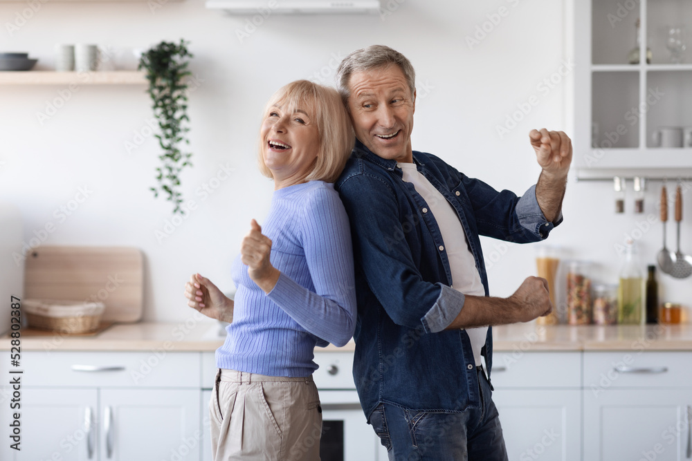 Joyful elderly spouses dancing together at kitchen Joyful elderly spouses dancing together at kitchen