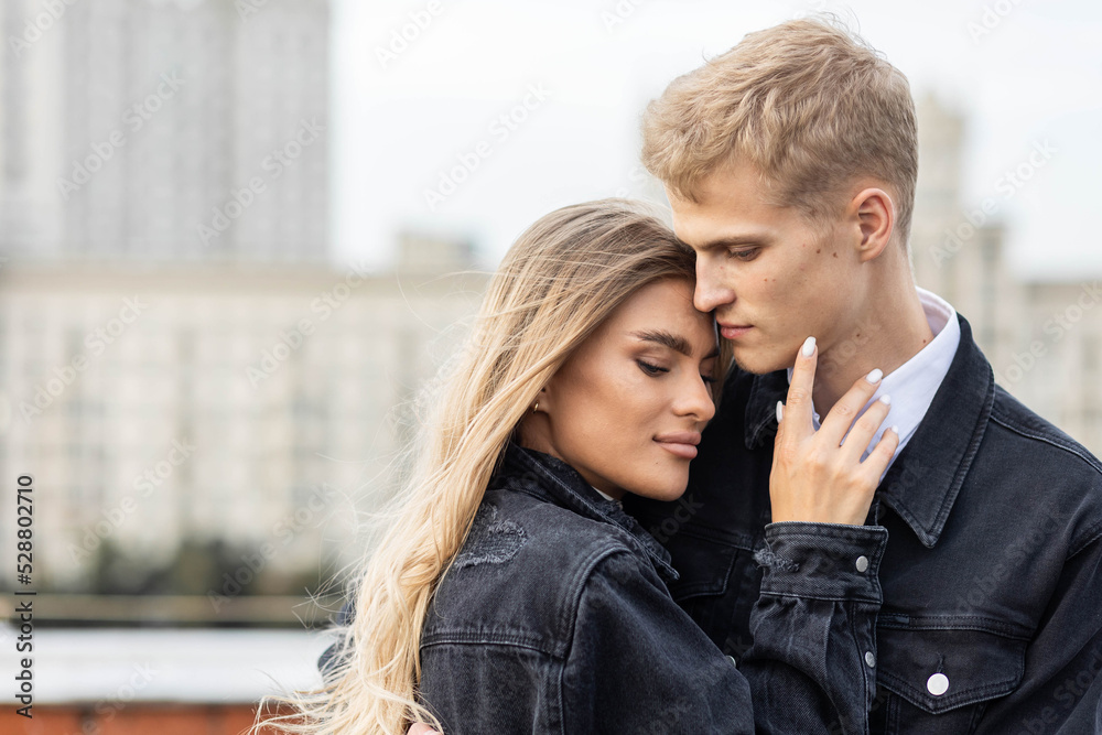 Beautiful happy young loving couple on a surprise date on a Saint Valentine's Day. Romantic modern wedding on the rooftop, summertime. Young man and beautiful girl. Newlyweds on honeymoon Beautiful happy young loving couple on a surprise date on a Saint Valentine's Day. Romantic modern wedding on the rooftop, summertime. Young man and beautiful girl. Newlyweds on honeymoon