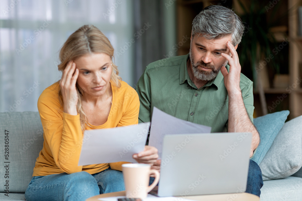Financial Crisis. Pensive Middle Aged Couple Checking Documents At Home Financial Crisis. Pensive Middle Aged Couple Checking Documents At Home