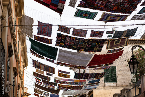 Photos Large colored crochet cloth suspended between the buildings of the city of Rossano in Calabria