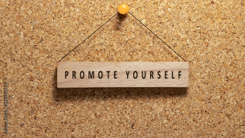 word promote yourself written on wooden surface. Hanging on wooden board. work and education.
